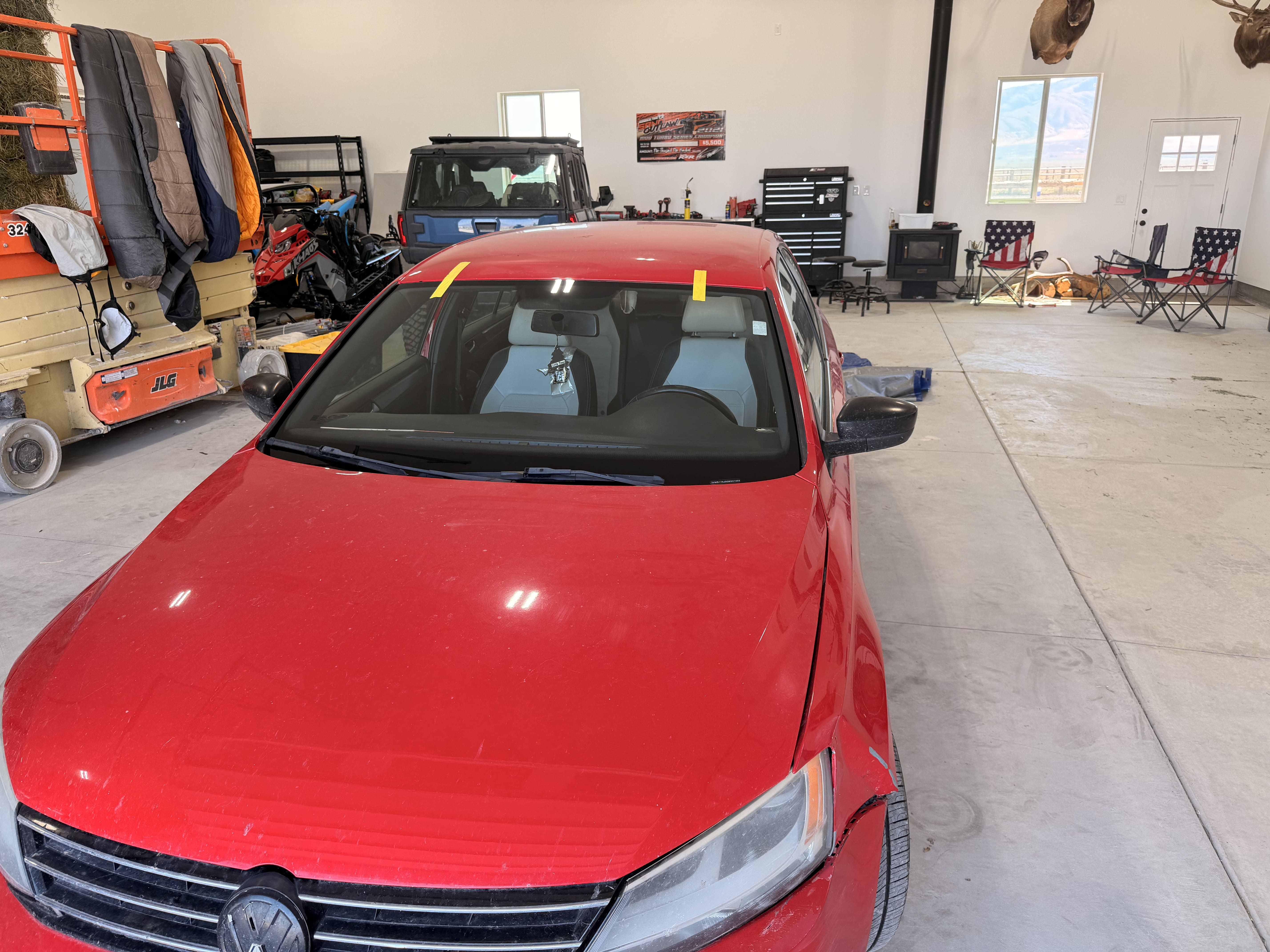 Red sedan prepared for windshield service in a workshop